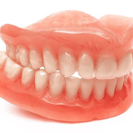 Close-up of full upper and lower dentures against white background