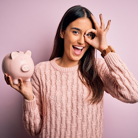 a woman holding a piggy bank and holding her fingers in the okay sign 