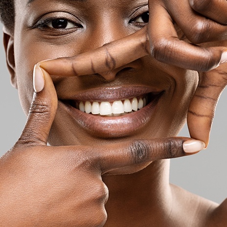 Woman framing her bright white smile with her fingers